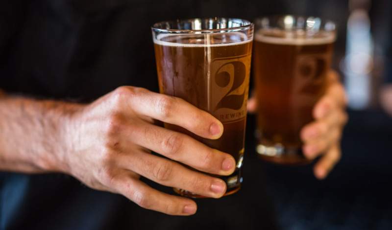 Server carrying two IPAs to a table outside